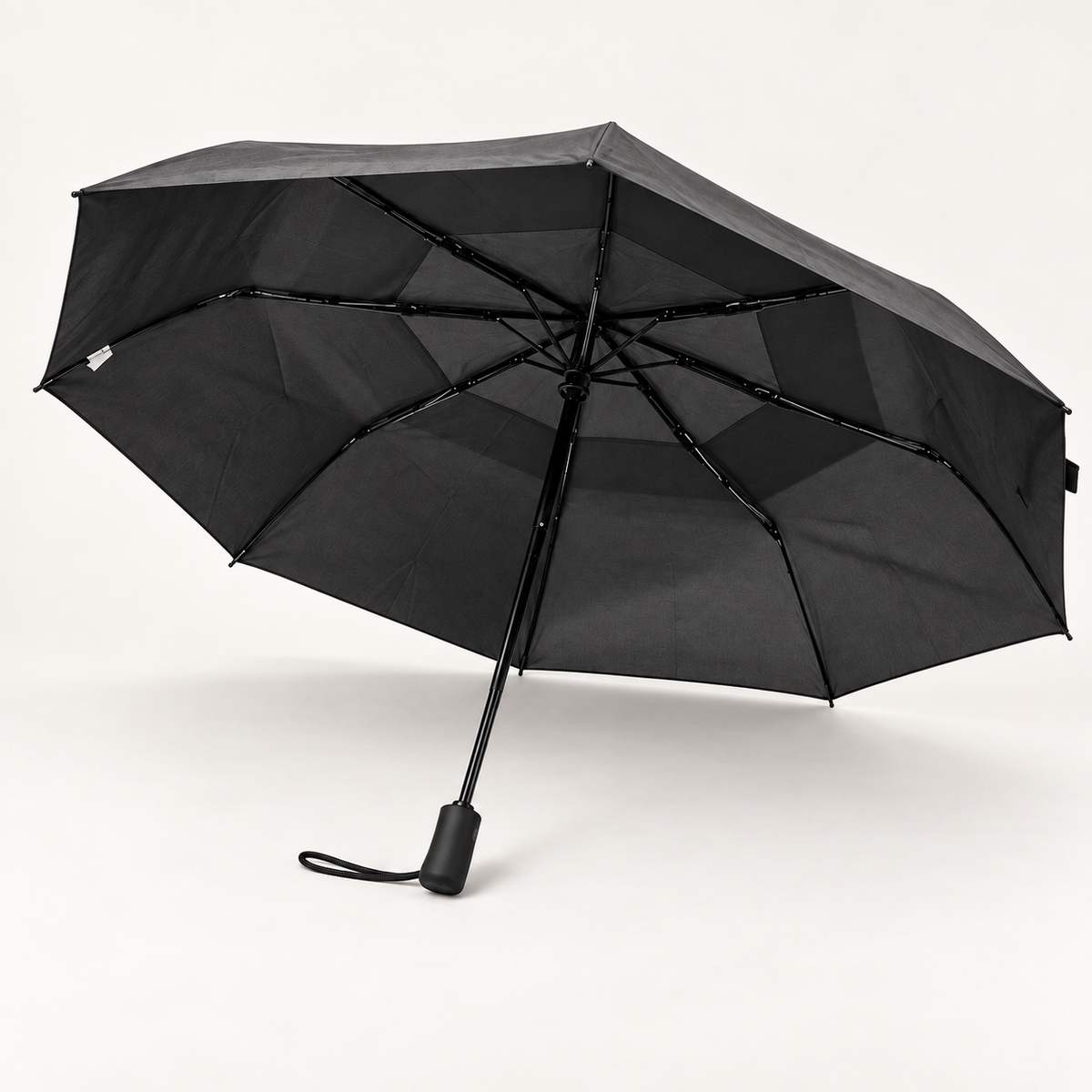 Black Flex Plus umbrella open, showing the vented canopy, ribs, handle, and wrist strap